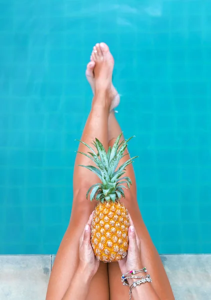 Schlanke Frau hält Ananasfrucht in der Nähe des Schwimmbades — Stockfoto