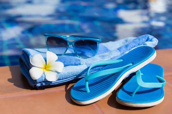 Blaue Hausschuhe, Sonnenbrille und Handtuch am Beckenrand — Stockfoto