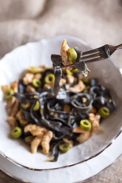 Pasta all'inchiostro nero con pollo e olive verdi — Foto Stock
