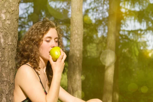 Jovem mulher bonita comendo maçã em um campo — Fotografia de Stock