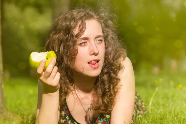 Giovane bella donna mangiare mela su un campo — Foto Stock