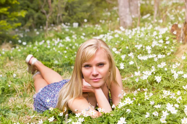 Vacker blond kvinna på en våren äng i blommor — Stockfoto