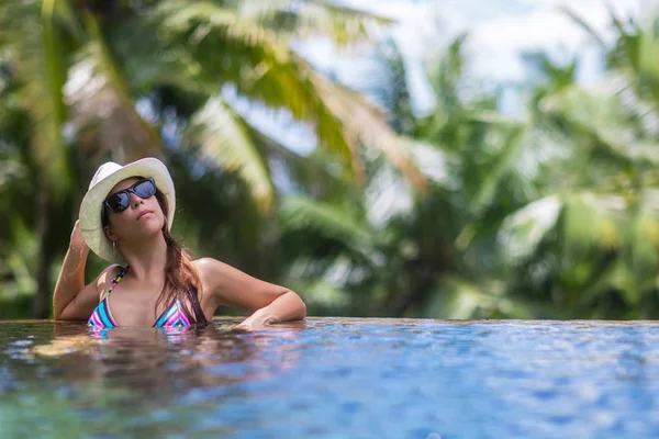 Frau mit Sonnenbrille sonnt sich im tropischen Pool — Stockfoto