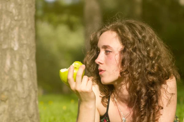Ung vacker kvinna äta äpple på ett fält — Stockfoto