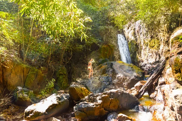 Junge Frau im Bikini steht auf Felswasserfall — Stockfoto