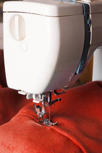 Šicí stroj a červené tkaniny — Stock fotografie
