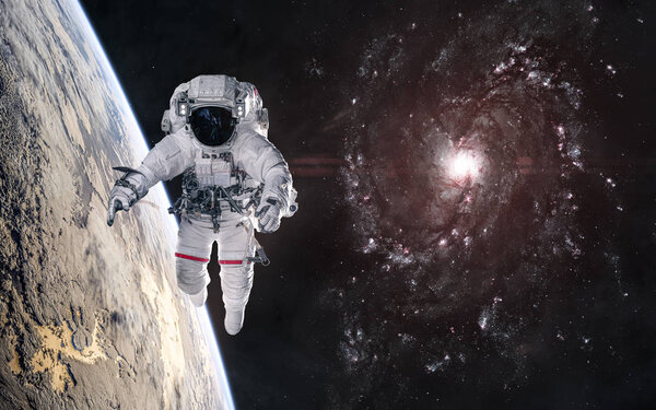 Астронавт на орбите планеты в глубоком космосе. Красная спиральная галактика
