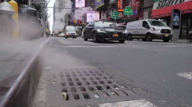 New York, Ocak 2020 - New York sokaklarındaki rögar kapağından çıkan buhar manzarası ön planda, arka plandaki araçlar bazı dükkanlar ve diğer buharlar arasında seyahat ediyor.