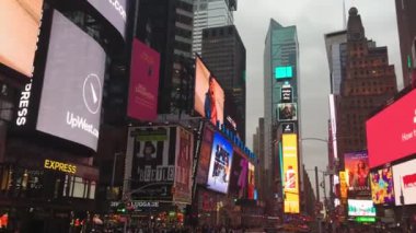 New York, Ocak 2020 - Times Meydanı 'ndaki reklam panolarında kameranın sağındaki panoramik hareket, New York' un ticari merkezi, kışın gri gökyüzünün altında