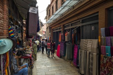 2015 'teki büyük depremde kısmen tahrip olan Bhaktapur çevresindeki tarihi işlek cadde boyunca yürüyen ve ticaret yapan ziyaretçiler.