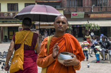 Tanımlanamayan keşiş bağış için ayakta duruyor ve Nepal 'deki ünlü Budist Tapınağı Boudhanath Stupa' da ilahiler söylüyor. Boudha Stupa dünyanın en büyük pagoda 'sı, dev Buda' nın gözleri 