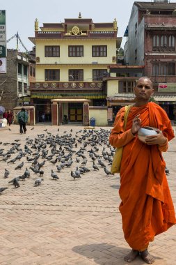 Tanımlanamayan keşiş bağış için ayakta duruyor ve Nepal 'deki ünlü Budist Tapınağı Boudhanath Stupa' da ilahiler söylüyor. Boudha Stupa dünyanın en büyük pagoda 'sı, dev Buda' nın gözleri 