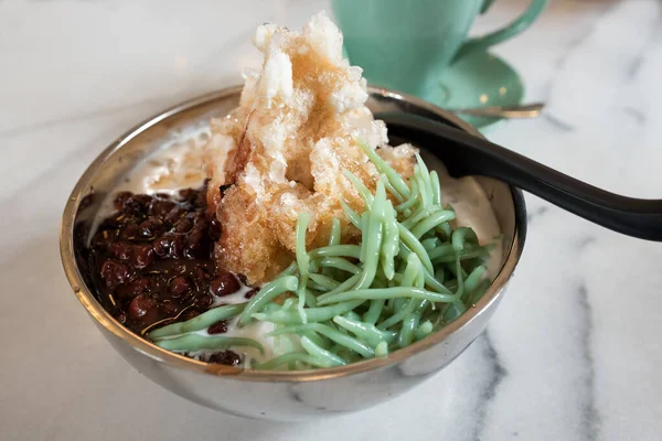 Delicious iced cendol with red beans. Cendol is an iced sweet dessert that contains droplets of worm-like green rice flour jelly, coconut milk and palm sugar syrup.