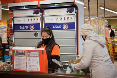 Yüzünde maskeyle süpermarkette kasiyer. Nisan 2020, Moskova.