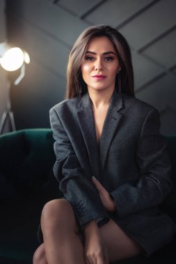 Ceketli bir kız bir dairede koltukta oturuyor.