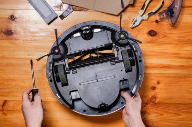 Robot bir elektrik süpürgesinin bakım ve hizmeti. Parçaların temizlenmesi, onarılması, değiştirilmesi