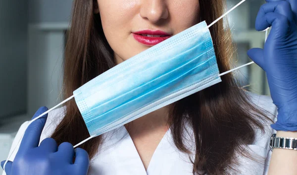Genç güzellik uzmanı kadın doktor yüzüne maske takıyor.