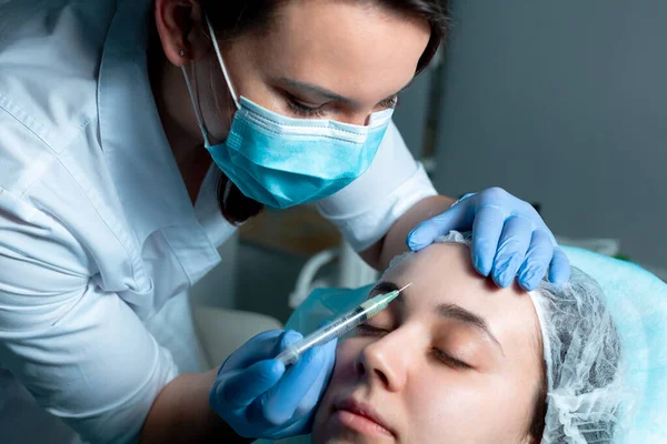 Beautician injects the drug into the forehead from wrinkles.