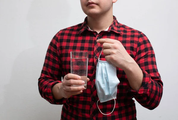 Pure water to prevent the spread of the virus. Man holds a medical mask and a glass of clean water