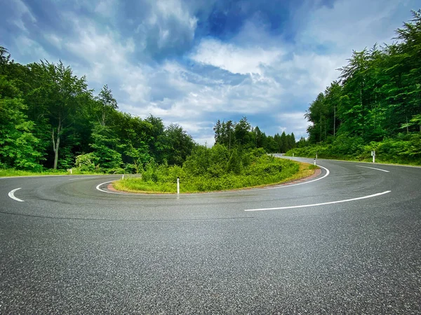 Hairpin Curve Through Forest, street in mountain range with tree area