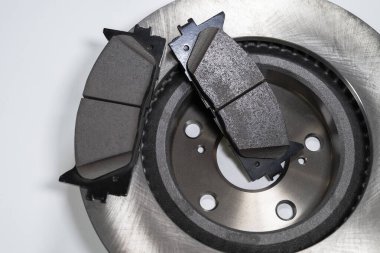 Beyaz bir masada fren yastıkları ve otomobil parçaları.