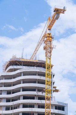 İnşaat halindeki işçilerle birlikte inşaat halindeki bir binanın arka planında vinçler.