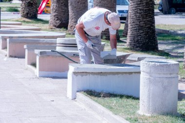 İşçi beyaz bir bank boyuyor.