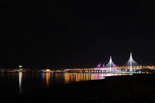 五彩缤纷的夜景，河上有一座灯火通明的桥 — 图库照片