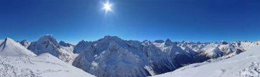 Karlı dağların panoramik manzarası bulutların tepesinde mavi gökyüzü Kafkaslar