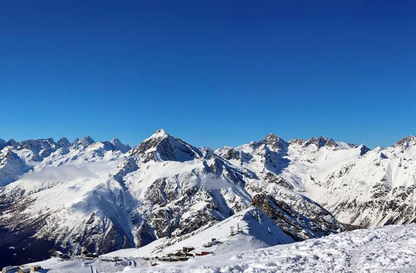 Vista panorámica de las montañas nevadas picos en las nubes cielo azul Cáucaso —  Fotos de Stock