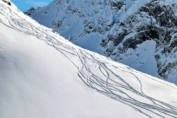 Pistas de snowboard en una montaña nevada en un día soleado — Foto de Stock