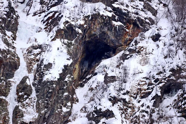 Penhasco coberto de neve e da caverna — Fotografia de Stock