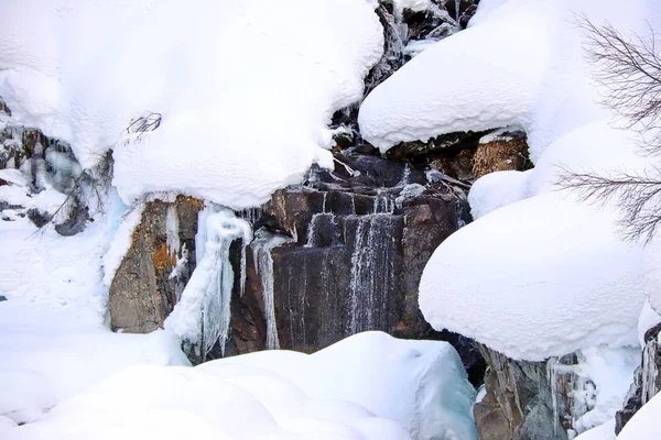 O córrego da montanha flui entre as rochas e a neve branca inchada nas margens — Fotografia de Stock