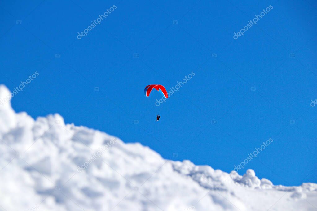 paraplane flying over snowy Caucasus mountains sunny blue sky