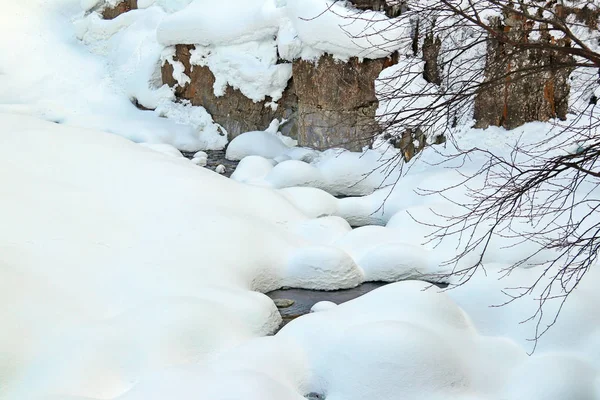 Horský potok teče mezi skalami a opuchlý bílý sníh na březích — Stock fotografie