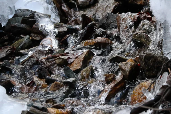 Córrego da montanha flui pedras secas, neve e gelo — Fotografia de Stock