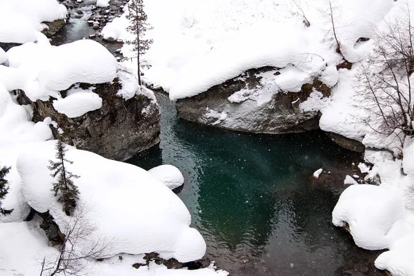 O córrego da montanha flui entre as rochas e a neve branca inchada nas margens — Fotografia de Stock