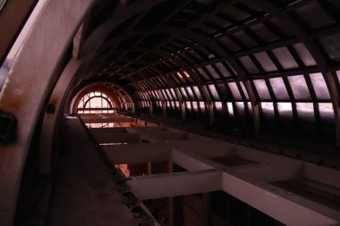 Terk edilmiş bir otelin ana salonunun cam kubbesinin altında.