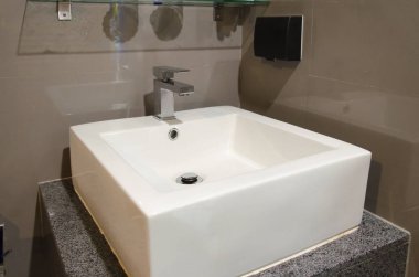 Banyo içi beyaz lavabo ve muslukla dolu.