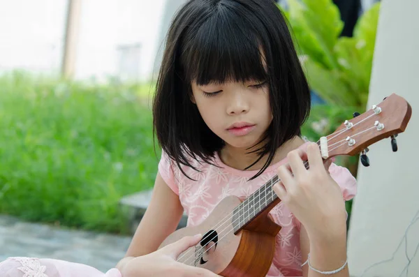 Asian girl playing the ukulele — Stock Photo, Image