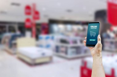 Alışveriş merkezinin arka planında çevrimiçi alışveriş kelimesiyle dokunmatik ekran akıllı telefonu tutmak.
