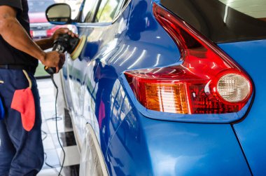 Otomatik cilalama. Mavi araba cilası arabayı kaldırır ve geri getirir. Arabanın stop lambalarına odaklan.