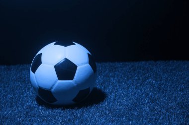Futbol topu çimenlere karşı siyah. Mavi filte