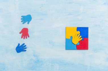 Renkli yapboz parçaları ve mavi arka planda eller. Dünya Otizm Farkındalık Günü Kavramı