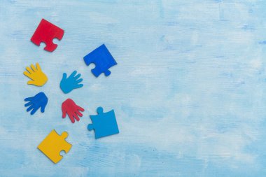 Renkli yapboz parçaları ve mavi arka planda eller. Dünya Otizm Farkındalık Günü Kavramı