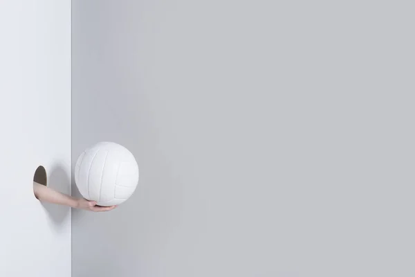把洞交出来 一个小孩的手拿着一个灰色和白色背景的白色排球球 — 图库照片