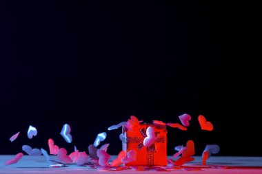 Pembe arka planda kalpleri olan bir hediye kutusu. Sevgililer Günü 'nde. mavi neon bayrak Sanat konsepti