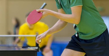 Elleri masa tenisi roketi ve topu tutan bir adamın yakınına.