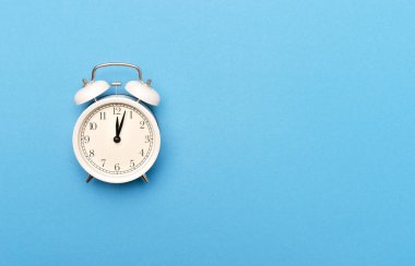Açık mavi arkaplanda beyaz klasik alarm saati