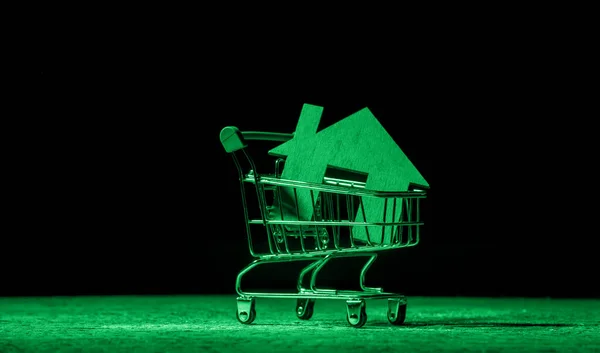超市推车里的木制房屋 买房子或公寓的概念 绿色过滤器 — 图库照片